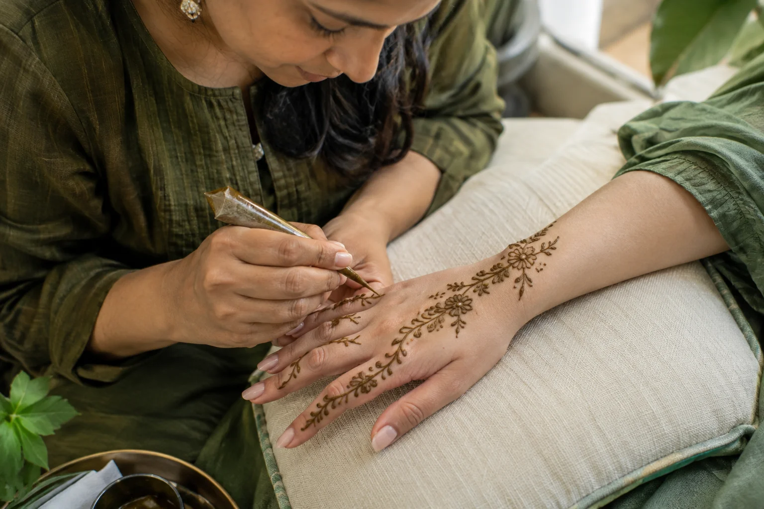 Mehendi artist decorating a hand